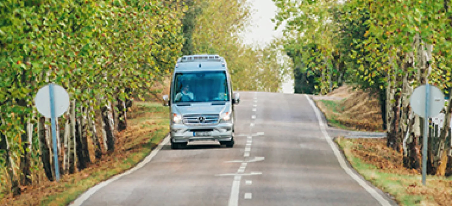 Blue-Roads mini-coach driving along a road.