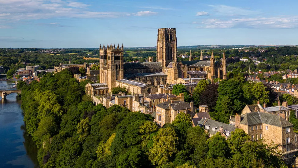 An aerial view of the impressive Durham Cathedral and the surrounding town at dusk.