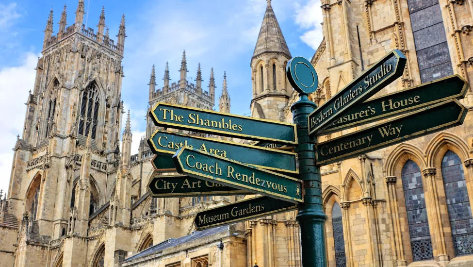 A view of a signpost detailing all the York highlights,  with York Cathedral in the background.