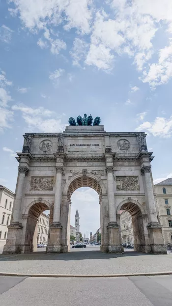 A view of the Siegestor in Munich, a grand ornate arch made of chiseled stone.