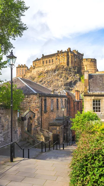 A view of Edinburgh's old town streets, with Edinburgh Castle towering above in the background.