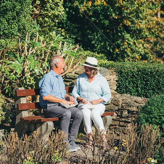 Two travellers enjoying a Cornish Pasty in a park.