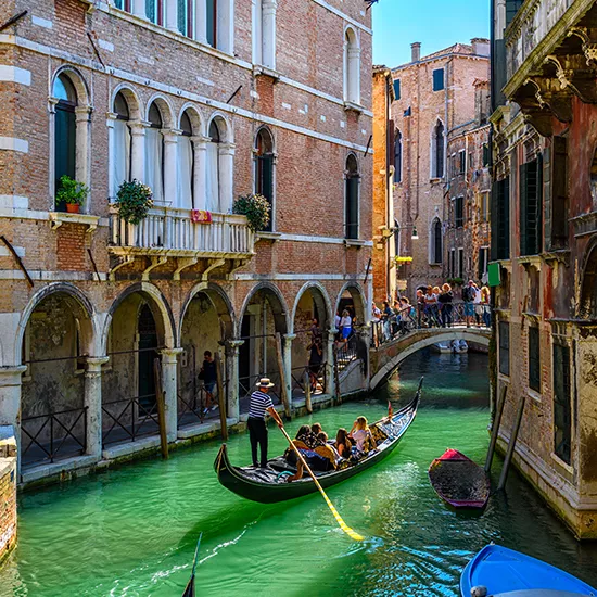 Gondolas cruise through the canals of Venice.